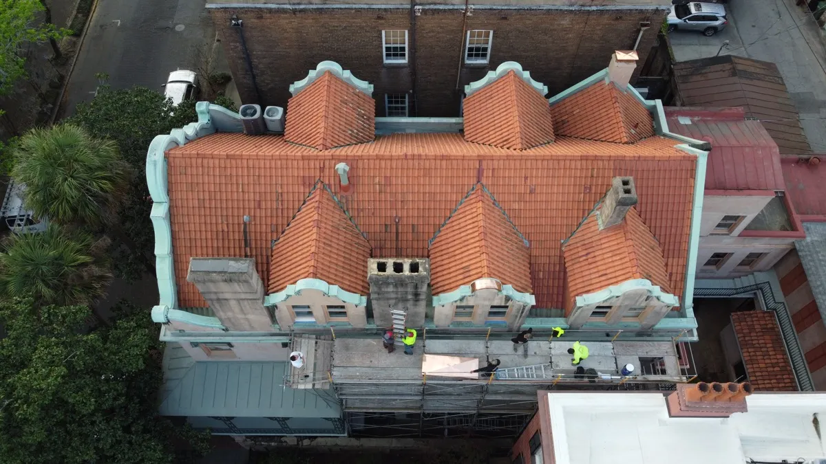 An aerial view of a Savannah tile roof with a crew working from scaffolding below