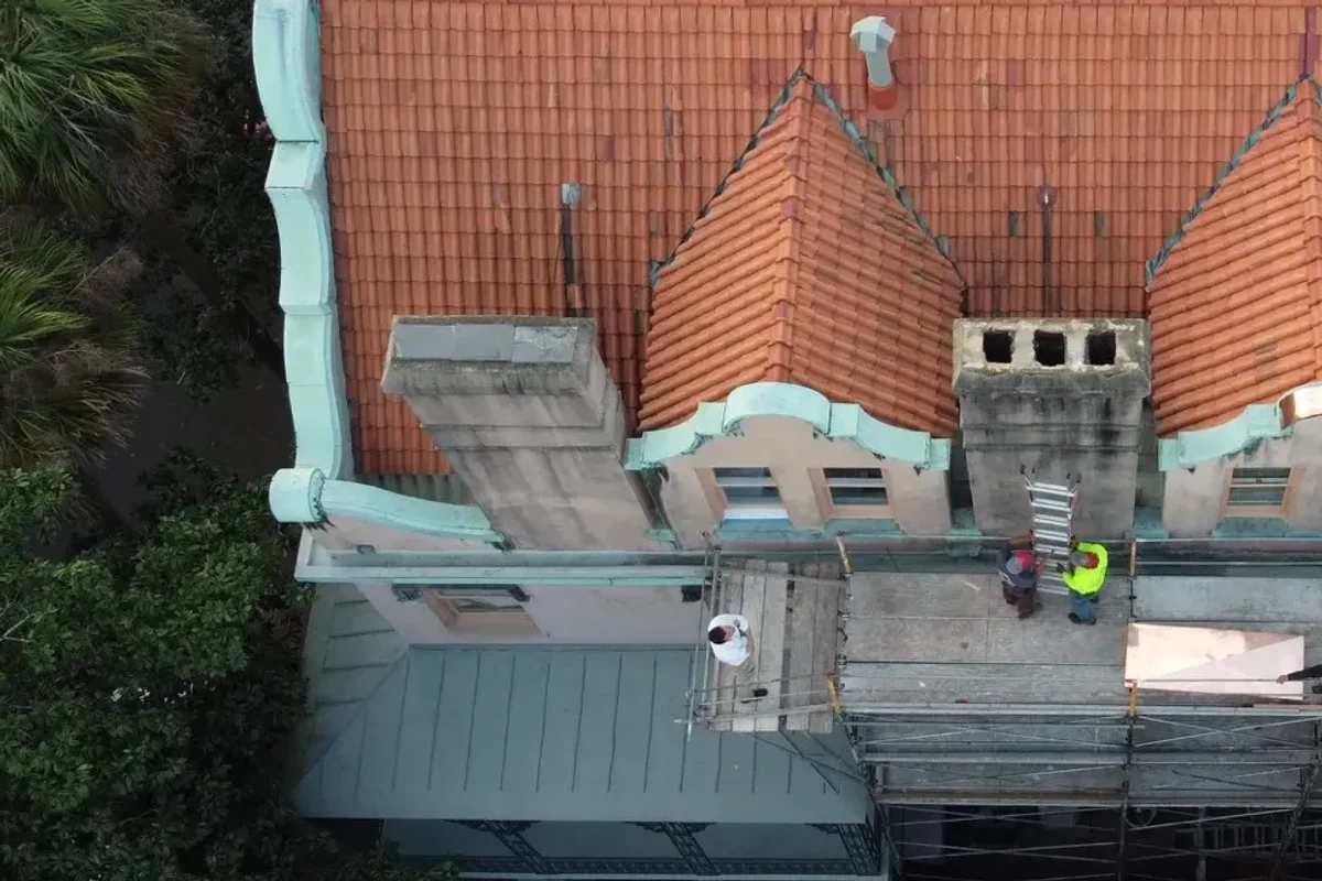 Crew restoring a tile roof with copper flashing on a historic Savannah row house