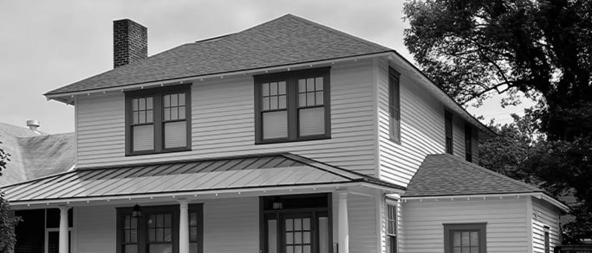 A white clapboard Savannah home with a standing seam metal porch roof
