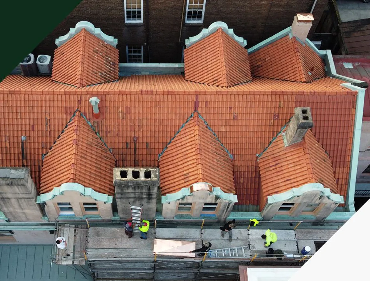 Crew restoring a terracotta tile roof with copper flashing on a historic Savannah building